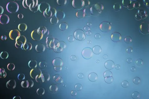 Real soap bubbles floating mid-air over blue background Foto stock