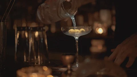 Real time close up shot of a bartender pouring a cocktail into a glass at a bar 스톡 동영상 129491654