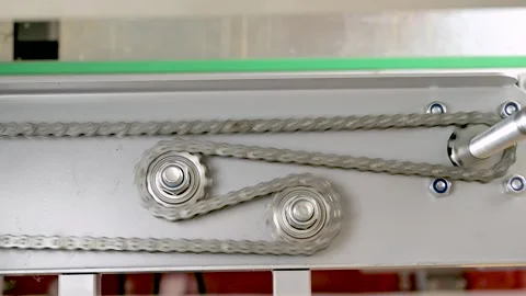 Real time closeup of a rotating system of gears and metallic chains on industry Stock Footage 296602466