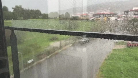 Real-time footage of heavy rain falling seen through a window screen Stock Footage 334780942