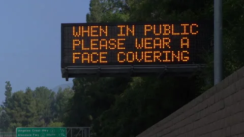 Real time long shot of a "please wear face covering" highway sign in Los Angeles Stock Footage 145380918