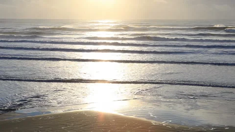 Real time long shot of the setting sun reflected in approaching waves Stock Footage 130232912