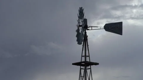 Real time profile view of a spinning windmill and rain clouds in west Texas Stock Footage 166875572