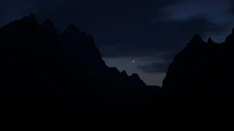 Real time shot of a crescent moon between silhouetted Grand Teton mountains 스톡 동영상 95457834