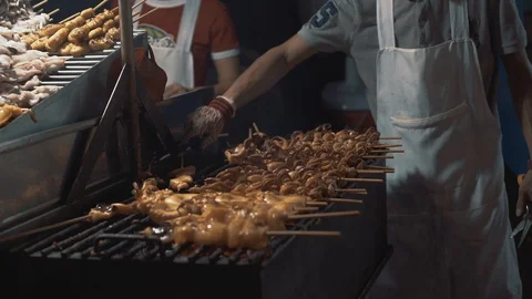 Real time shot of a man cooking seafood on a grill at a market at night in 스톡 동영상 129485532