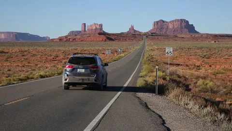 Real Time of an SUV driving toward Monument Valley on a sunny morning Stock Footage 253240382