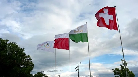 Real time of Swiss and Olympic Flags Flying in Windy Weather over Lake Geneva Stock Footage 336575848