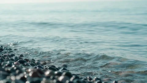 Real time video capturing gentle waves flowing over a sunlit pebble beach, Stockbeeldmateriaal 330376853