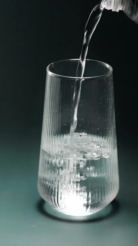 Real-time video showing fresh clear water flowing into a textured glass tum.. Видео 345125458