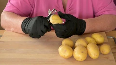 Real time video of a womans hands in black gloves to peeling potatoes Stock Footage 129178707