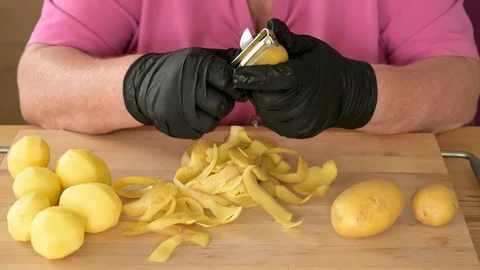 Real time video of a womans hands in black gloves to peeling potatoes Stock Footage 129191795