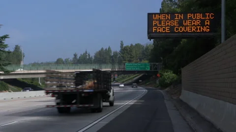 Real time wide shot of a "please wear face covering" highway sign in Los Angeles Stock Footage 133387457