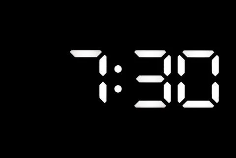 Real white led digital clock on black background Stock Photos