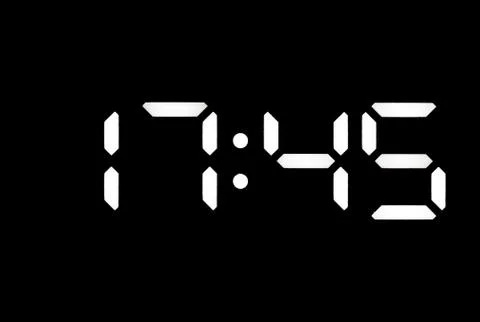 Real white led digital clock on black background Stock Photos
