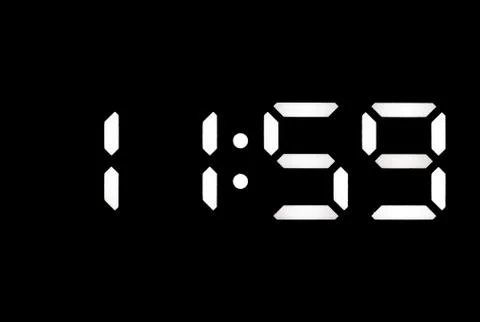 Real white led digital clock on black background Stock Photos