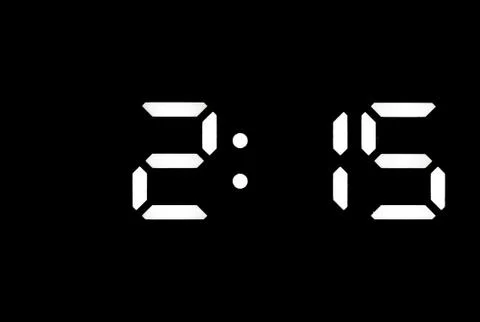 Real white led digital clock on black background Stock Photos
