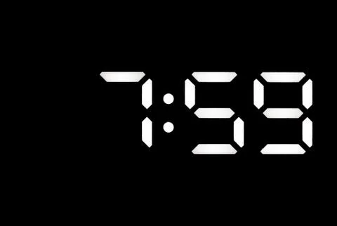 Real white led digital clock on black background Stock Photos