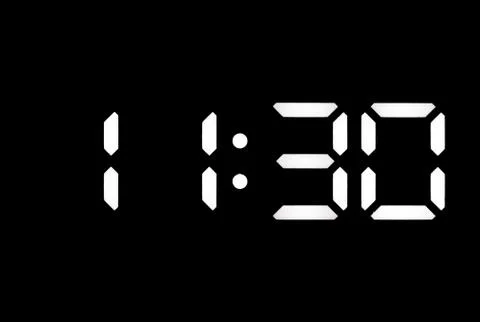 Real white led digital clock on black background Stock Photos
