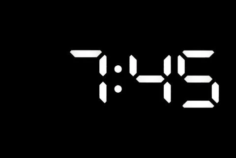 Real white led digital clock on black background Stock Photos