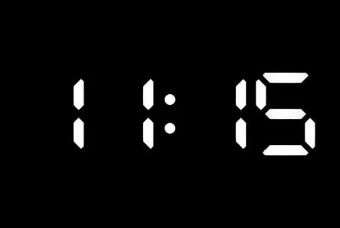 Real white led digital clock on black background Stock Photos