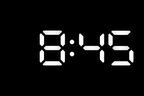 Real white led digital clock on black background Stock Photos