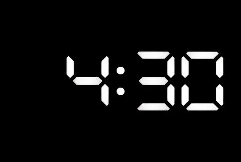 Real white led digital clock on black background Stock Photos