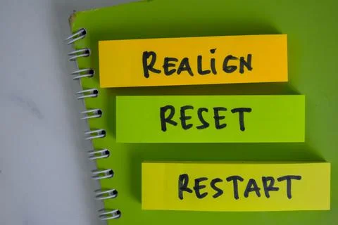 Realign, Reset, Restart write on sticky notes isolated on Wooden Table. Stock Photos