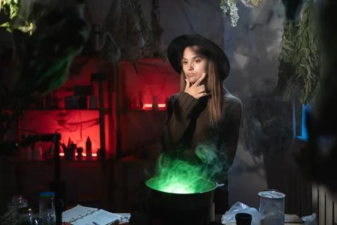 Realistic witch brewing a potion in cauldron thinking mystical idea. Blend of Stock Photos