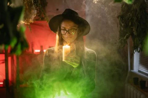 Realistic witch brewing potion. She leans over cauldron, letting wax drip f.. Fotos de archivo