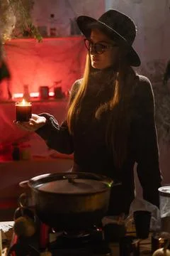 Realistic witch brewing potion. She leans over cauldron, letting wax drip f.. Fotos de archivo
