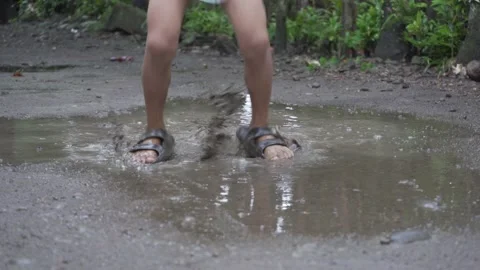 Realtime 23fps 4k Resolution of Kid Playing and Jumping in the Puddle of Mud Stock Footage 132637899