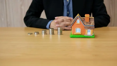 Realtor agent with coins stack house model offering key. Stock Footage 106052417