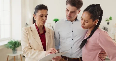 Realtor guiding couple through contract paperwork during purchase consultation Stock Footage 342146011
