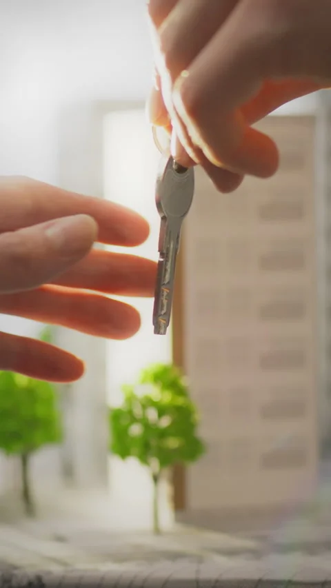 Realtor hands over keys in vibrant urban environment surrounded by modern ar Stock Footage 331725816