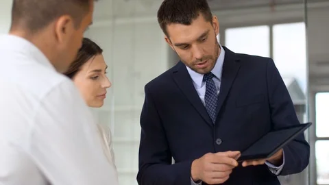 Realtor showing tablet pc to customers at office Stock Footage