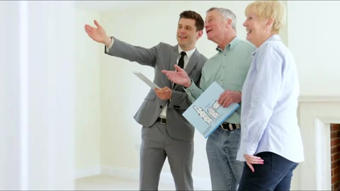Realtor Shows Senior Couple Downsizing Around Retirement Home Stock Footage 130700968