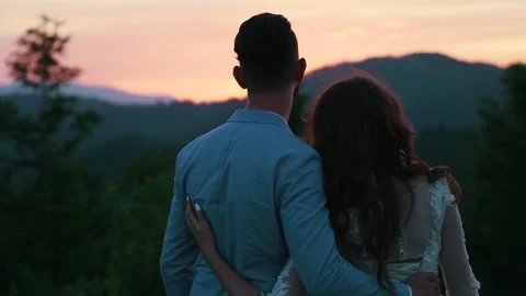 Rear back view of young couple, hugging against backdrop of sunset. Slow motion Stock Footage 211807594