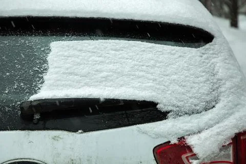 Rear car window covered with a layer of snow blocked windshield wiper. Stock Photos