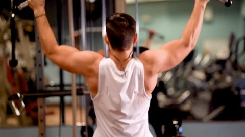 Rear closeup of young bodybuilder doing lat pulldowns on a machine. Stock Footage 98288056