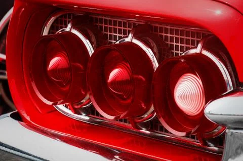 Rear cluster of an old timer luxury sports car with three tail lights with red Stock Photos