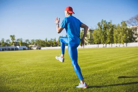 Rear horizontal view of active young male athlete running and jogging alone a Stock Photos