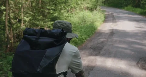 Rear over-the-shoulder view of cyclist on forest road Stock Footage 311920272