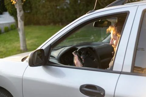Rear side view of a  man using his smartphone and texting while stop driving Stock Photos