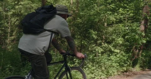 Rear tracking shot of cyclist on forest road Stock Footage 311934890