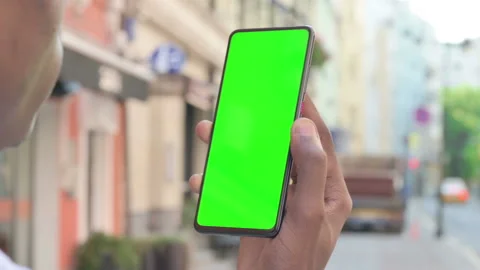 Rear View of African Man Looking at Smartphone with Green Chroma Screen Stock Footage 159706641