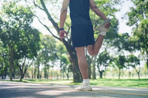Rear view of athlete stretching quad muscle on park trail for fitness warmup Stock Photos