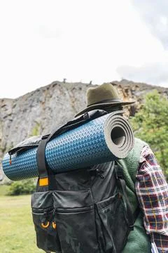 Rear view of a backpacker with hat and mat in nature. Independent lifestyle Stock Photos