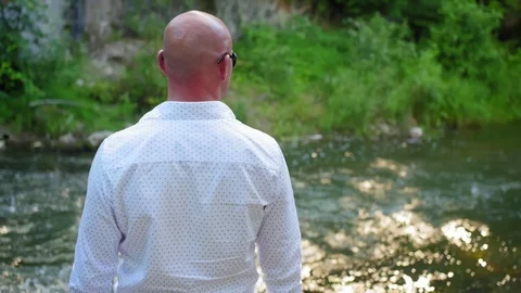 Rear view of a bald man looking at a river. Medium shot. Stock Footage 115026752