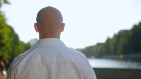 Rear view of bald man standing in a park and looking ahead. Close up shot. Stock Footage 112623515