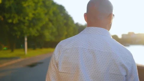 Rear view of bald man standing in a park and looking ahead. Close up shot. Stock Footage 112831359